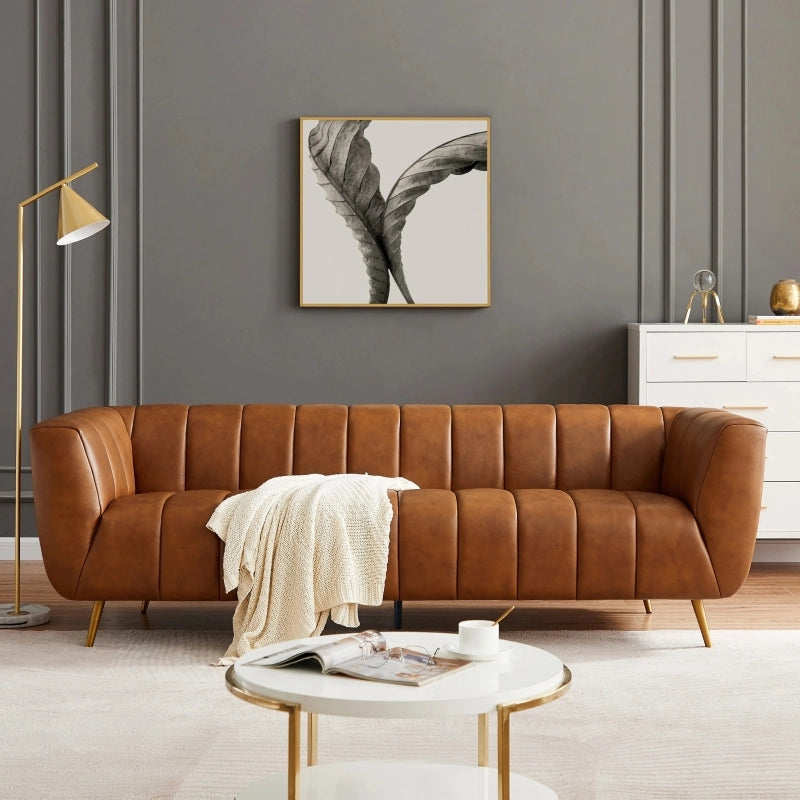 Front angle view of Sabryn leather sofa featuring luxury leather couch styling, leather sofa set comfort, vertical channel tufting, brass finish legs, modern sofa design and elegant living room sofa appeal