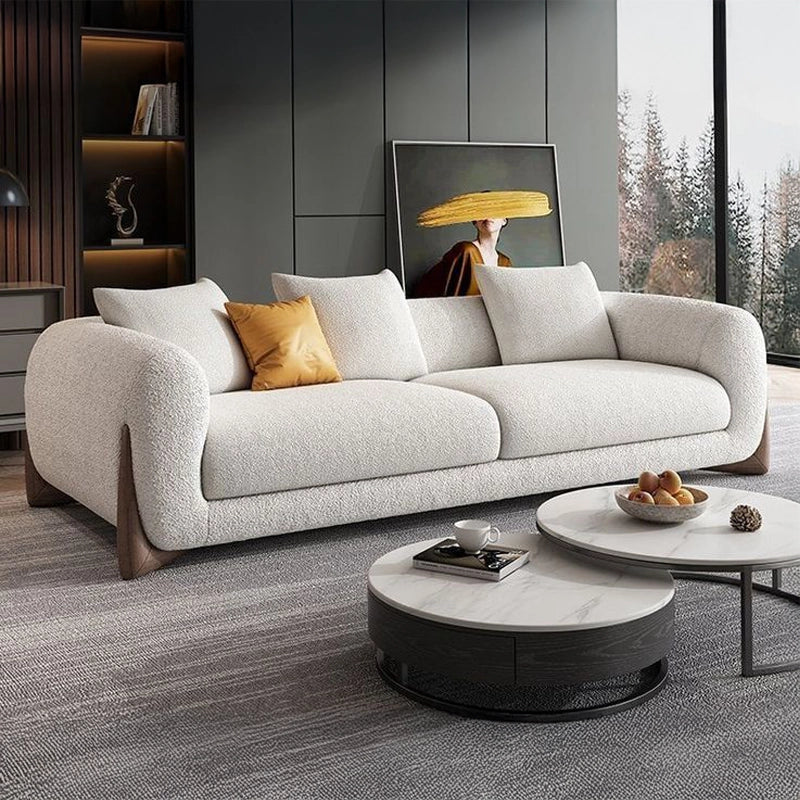 Modern living room with a gray sofa, round marble coffee table, and decorative elements.