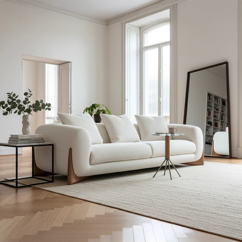 Modern living room with a white sofa, round marble coffee table, and decorative elements.
