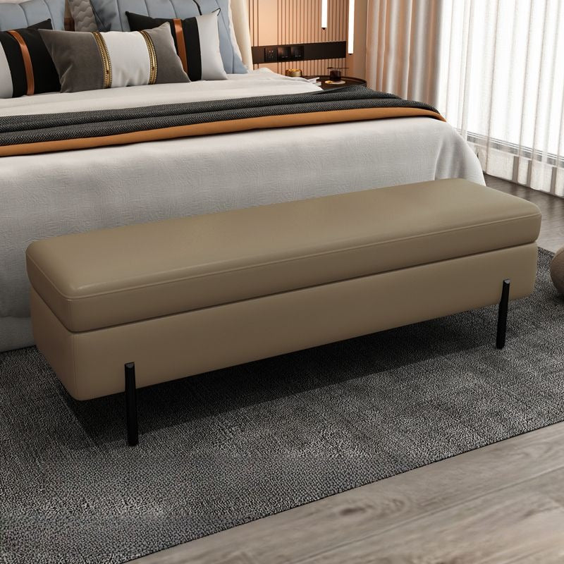 The rectangular shape with a padded faux leather top is supported by matte black metal legs, giving it a floating, minimal look.