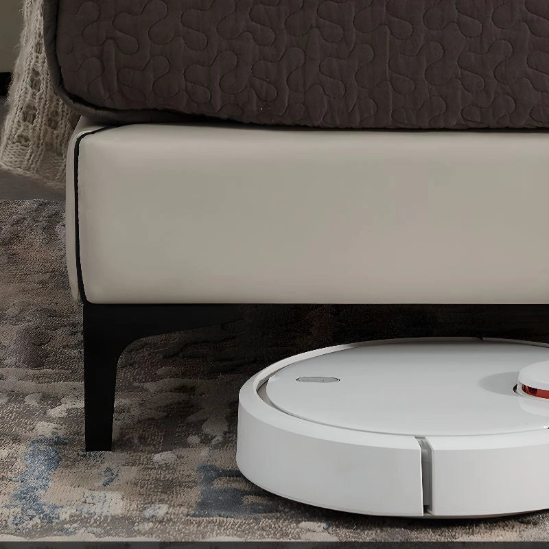 A segmented and padded headboard, finished in beige leatherette with dark piping, offers ergonomic support while anchoring the minimalist shape