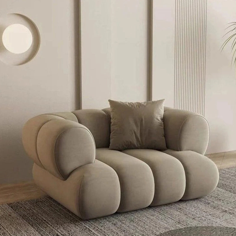The channel tufted backrest and pillowy arm design give it a lounge sofa charm, while the low profile silhouette and hidden legs underscore its designer appeal.