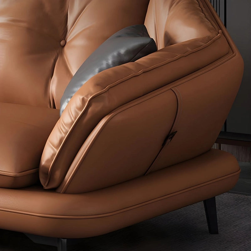 Brown leather armchair with a gray pillow on a dark background