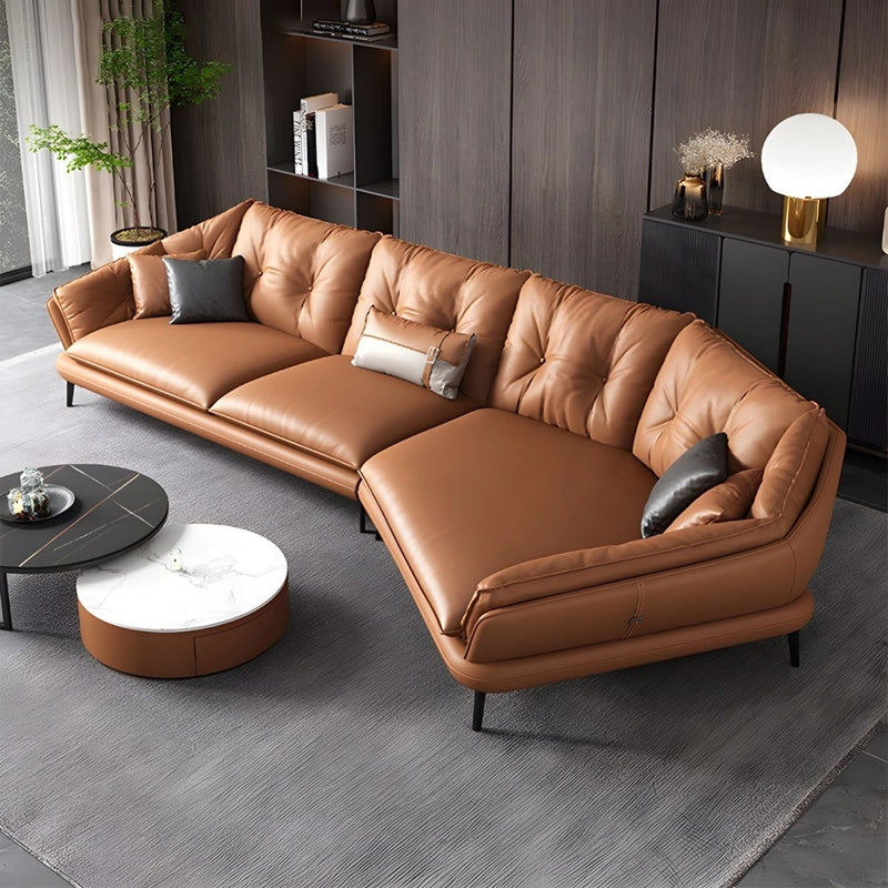Brown leather sectional L shaped sofa in a modern living room setting with a coffee table and decorative items.