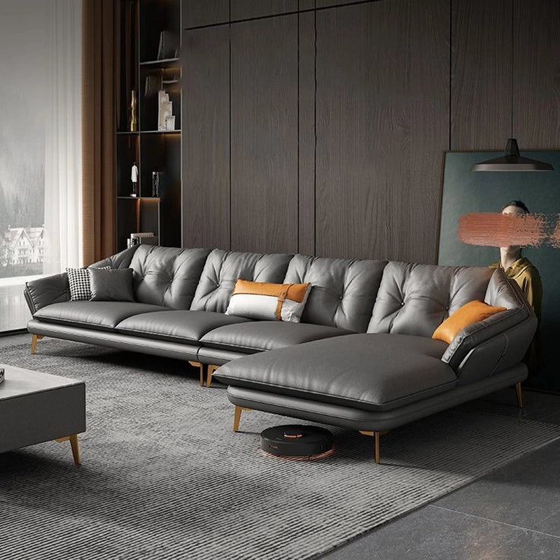 Gray sectional L shaped sofa in a modern living room with wooden walls and a rug.