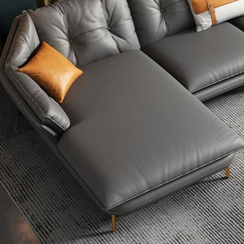 Gray sectional L Shaped sofa with orange pillow on a textured gray carpet