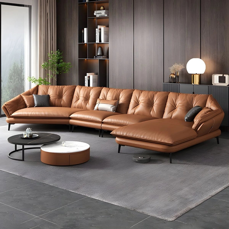 Brown leather sectional L Shaped sofa in a modern living room with gray rug and decor.